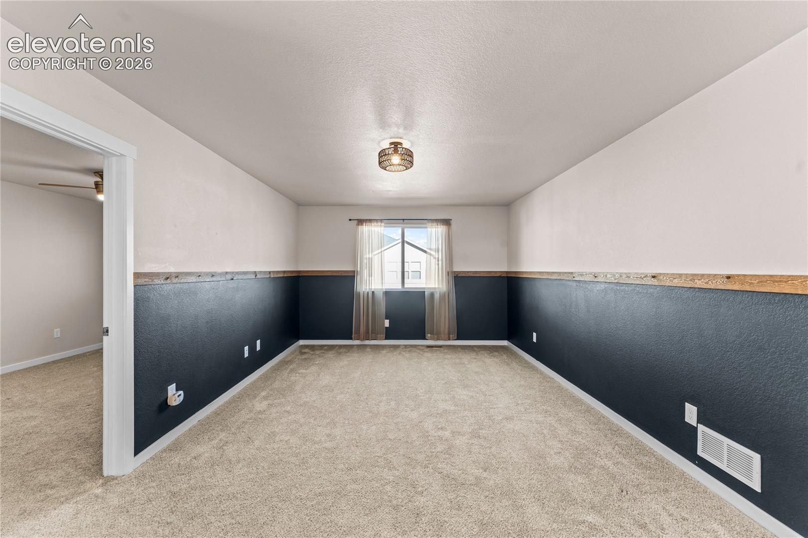 Interior room featuring two-tone wall paint with a wooden chair rail, neutral wall-to-wall carpeting, and a flush-mount drum ceiling light fixture
