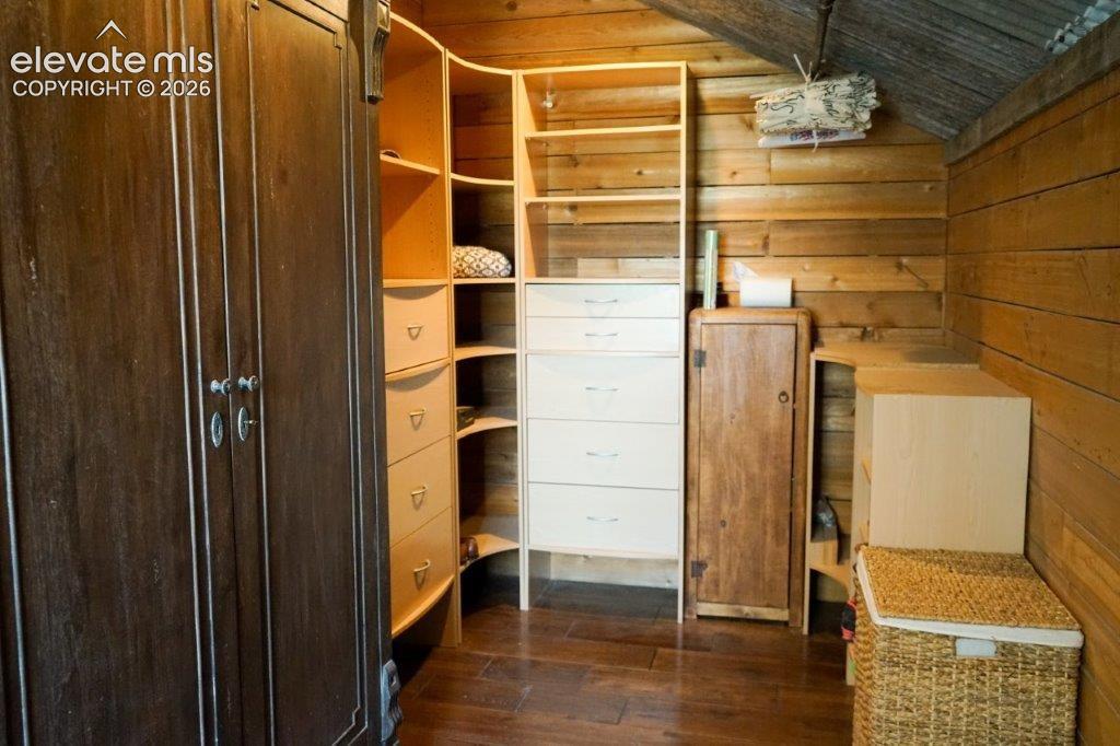 Built-in closet system featuring multiple shelves and drawers, dark wood-finish flooring, and natural wood-paneled walls