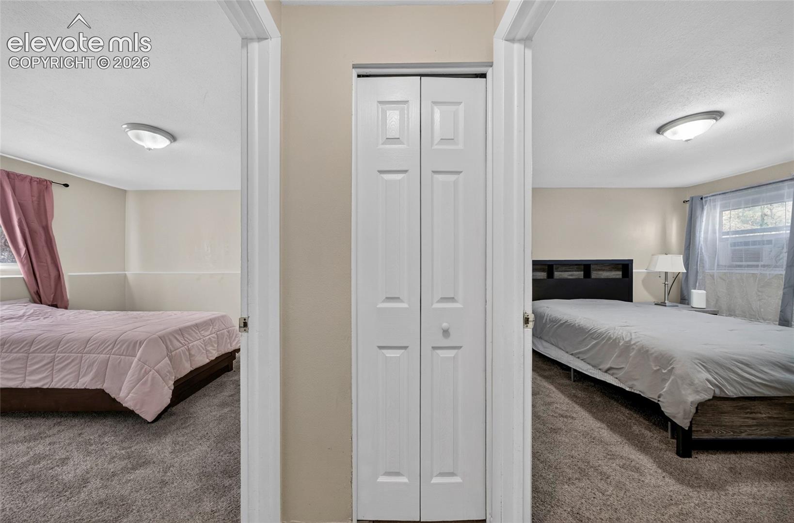 Interior space featuring neutral wall tones, wall-to-wall carpeting, white bi-fold closet doors, and flush-mount ceiling lighting