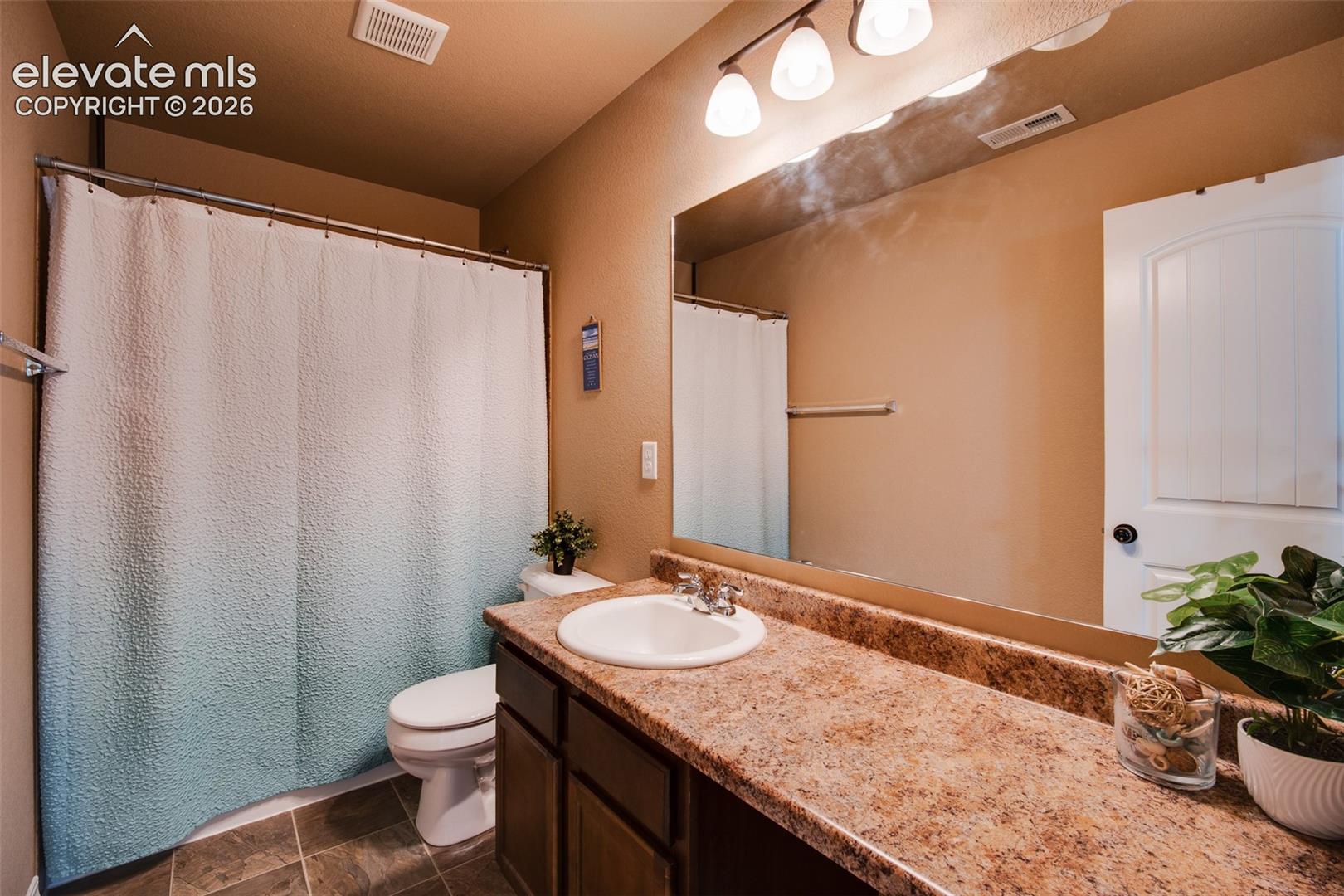 Upper Level Full Bathroom with a tile floor, extended vanity, mirror, and tiled tub/shower.