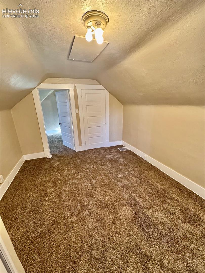 Carpeted flooring, sloped ceiling, flush mount ceiling light, and white trim