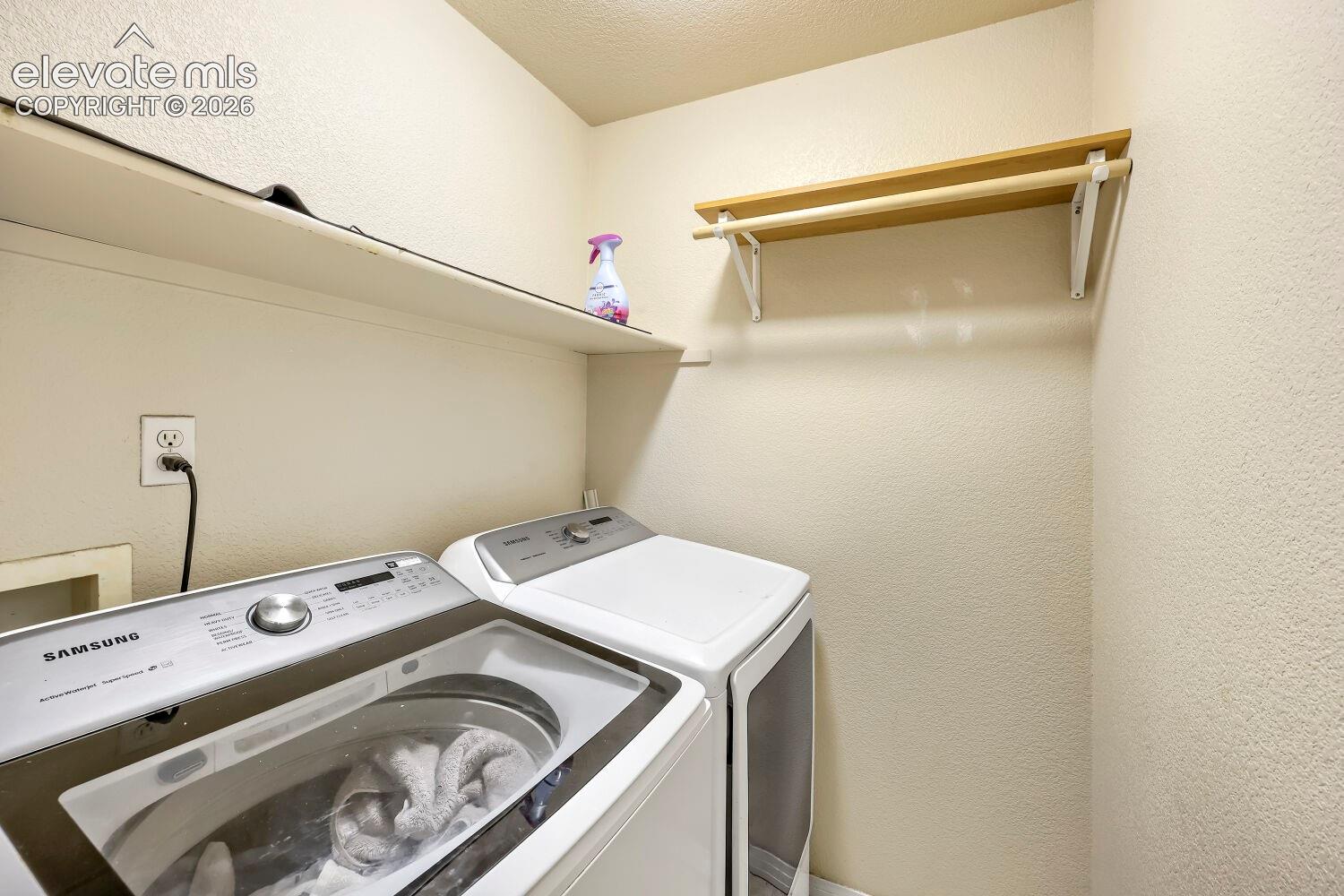 Dedicated laundry space featuring a built-in shelving unit and a clothes hanging rod
