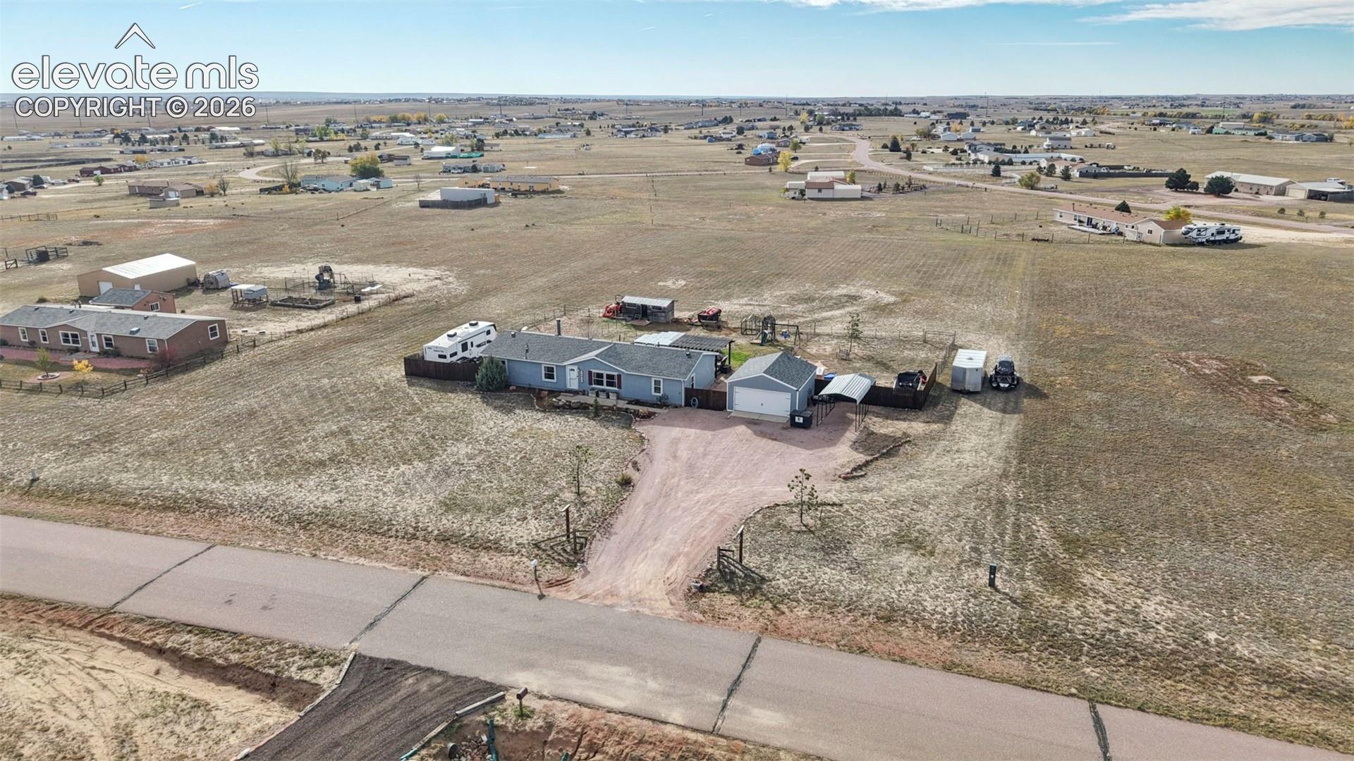 Detached residence featuring a gravel driveway, fenced perimeter, and a standalone garage structure situated on an expansive lot