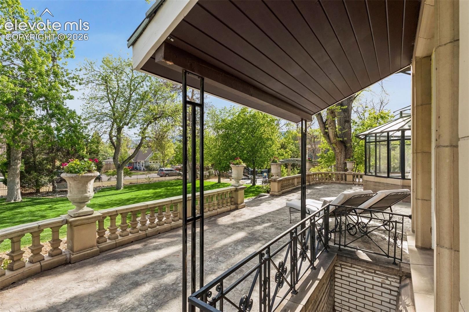 South Porch: A spacious open porch overlooking the lawn’s fountains and pergola, surrounded by a low balustraded stone railing.
