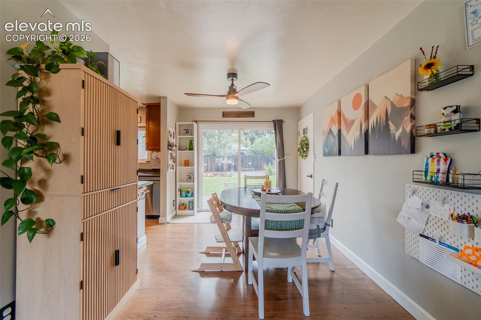 Wood-finish flooring, ceiling fan with integrated lighting, and sliding glass door with exterior access