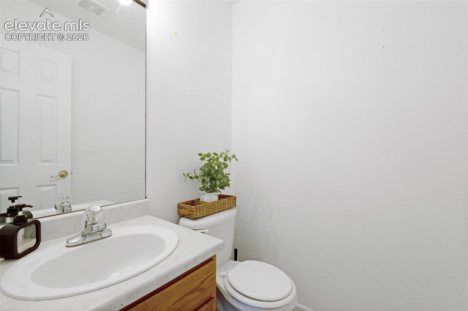 White paneled door with brass-finish hardware, built-in vanity with laminate countertop, oval sink, and chrome-finish faucet