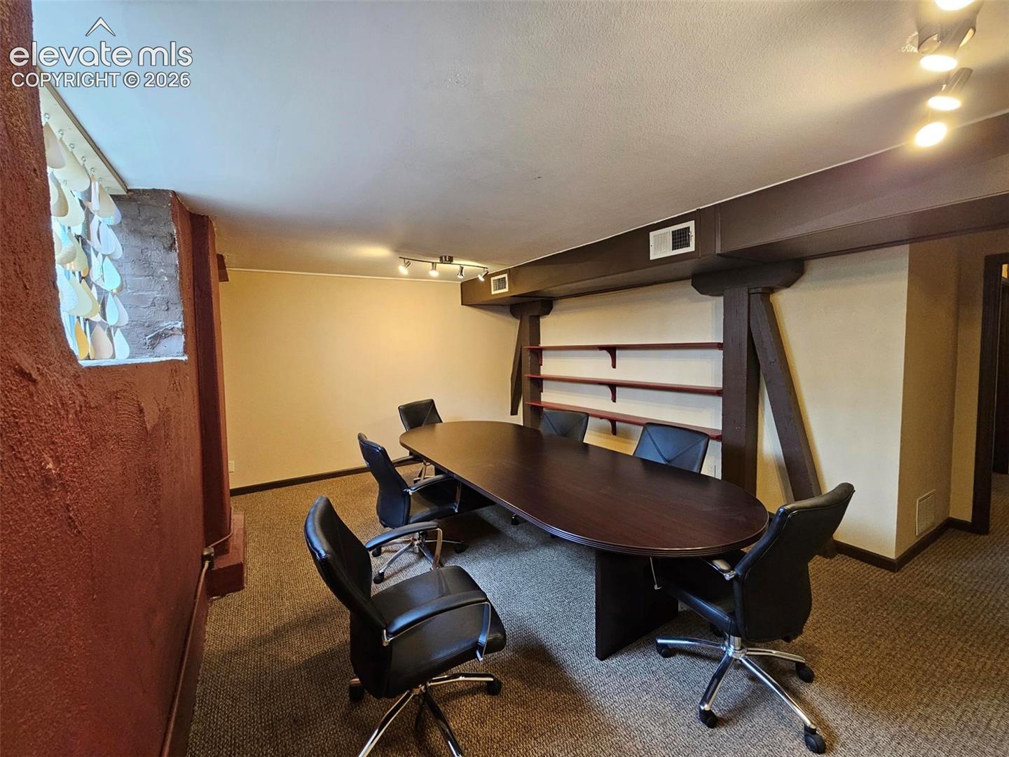 Conference room featuring track lighting, built-in shelving, exposed support beams, and carpet flooring