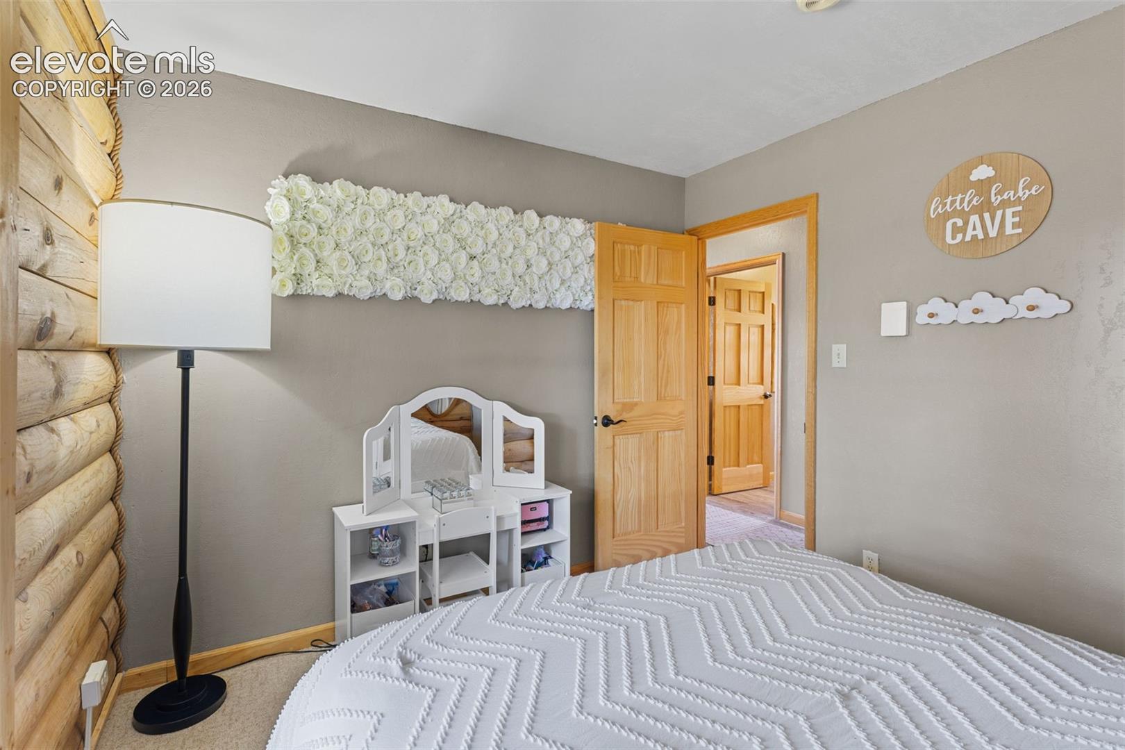Interior room featuring a horizontal log wall, natural wood six-panel doors, and neutral wall tones