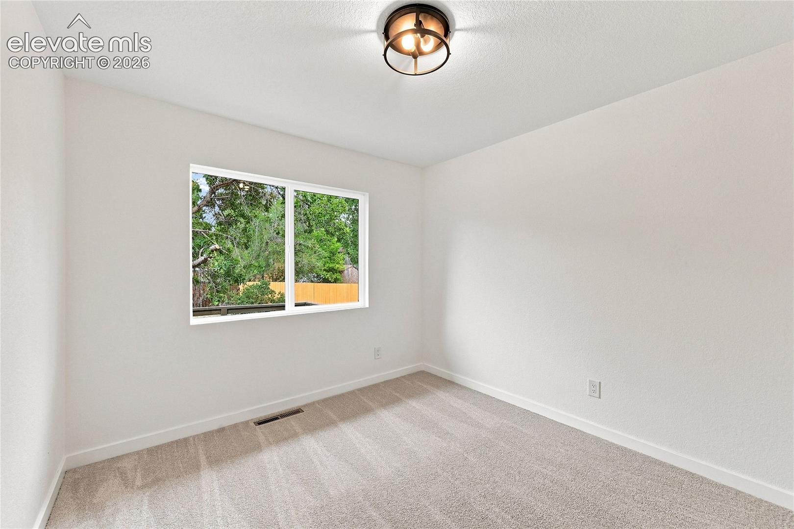 Recessed window with white trim, light neutral carpeting, and a flush mount ceiling light fixture