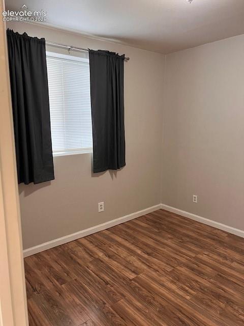 Neutral-toned interior space featuring wood-finish flooring and a single window with integrated horizontal blinds