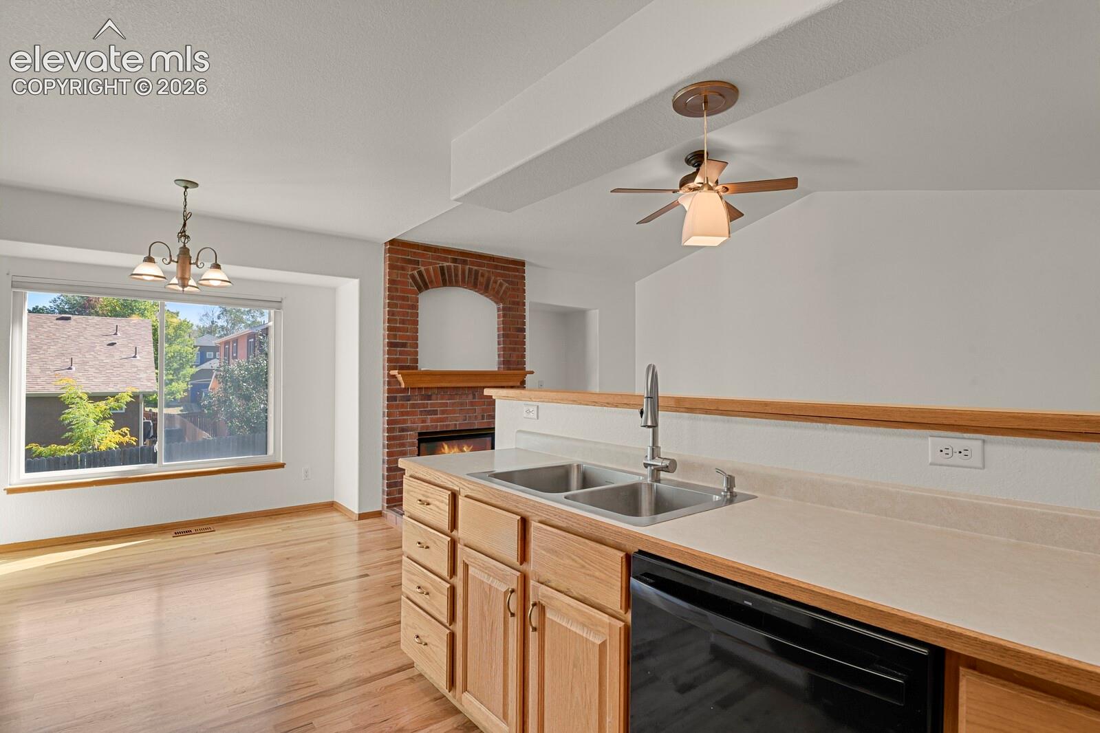 Kitchen with wood-finish cabinetry, stainless steel double-basin sink, and black appliance