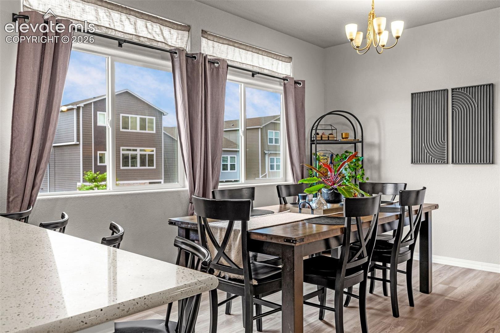 Bright dining area featuring a gold chandelier, light gray walls, and wood-finish flooring