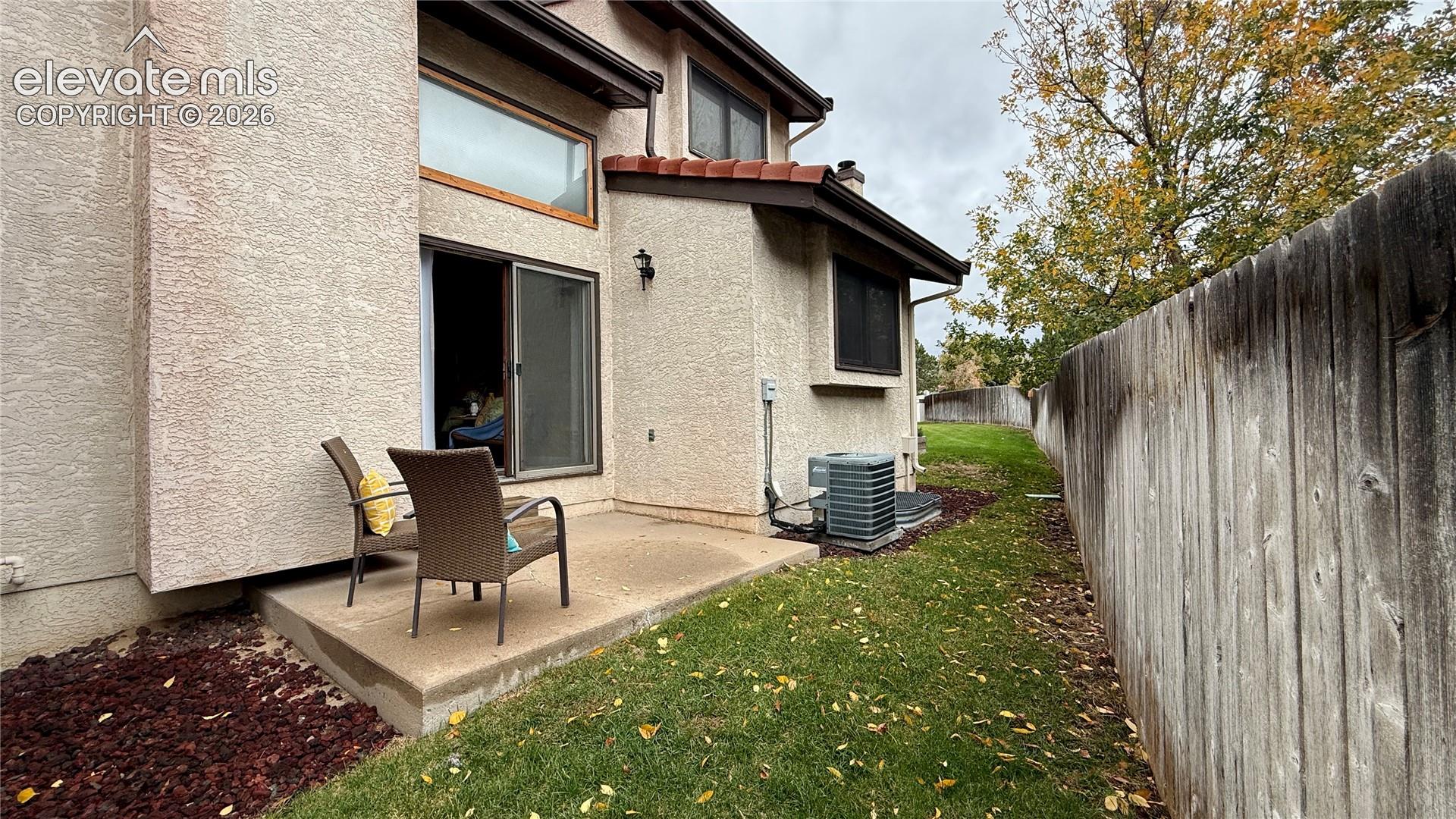 Stucco exterior featuring a concrete patio, wood-style privacy fencing, and tile look roof accents