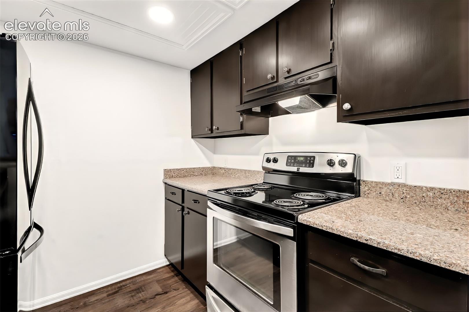 Kitchen featuring stainless steel electric range, built-in range hood, quartz countertops and luxury vinyl plank flooring.