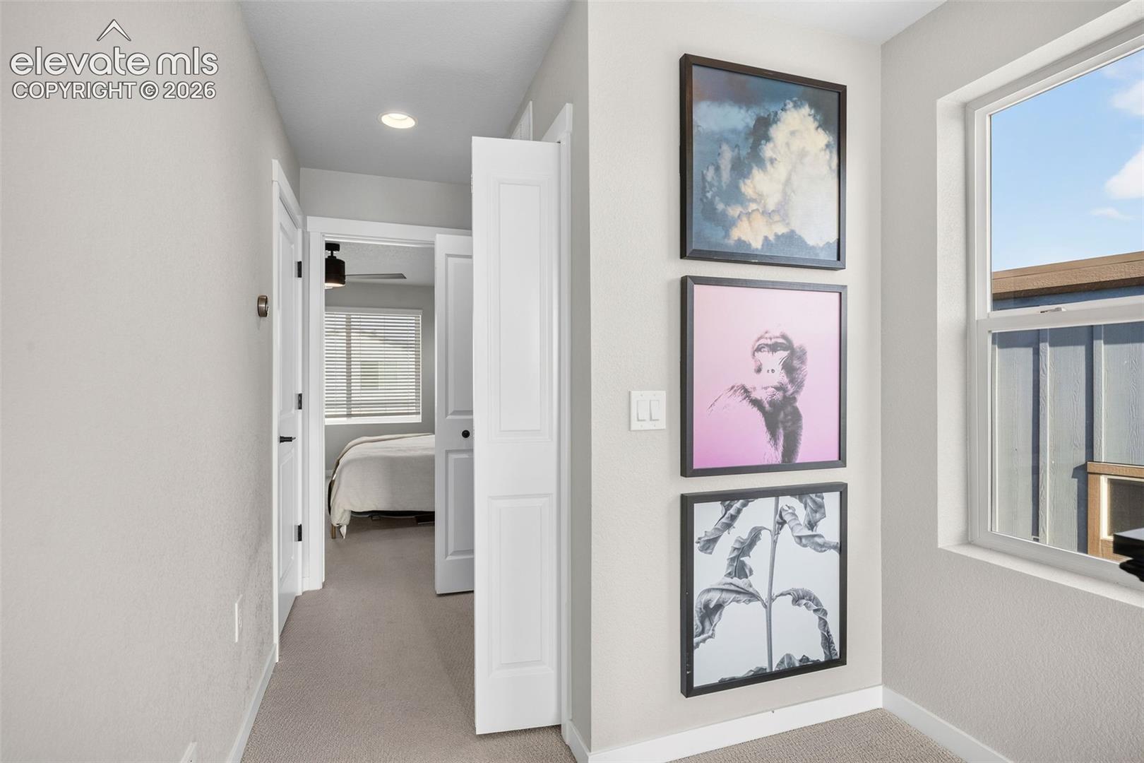 Upstairs, the hallway bright with an oversized window. The primary suite is at the end of the hallway with the laundry room to the right. 