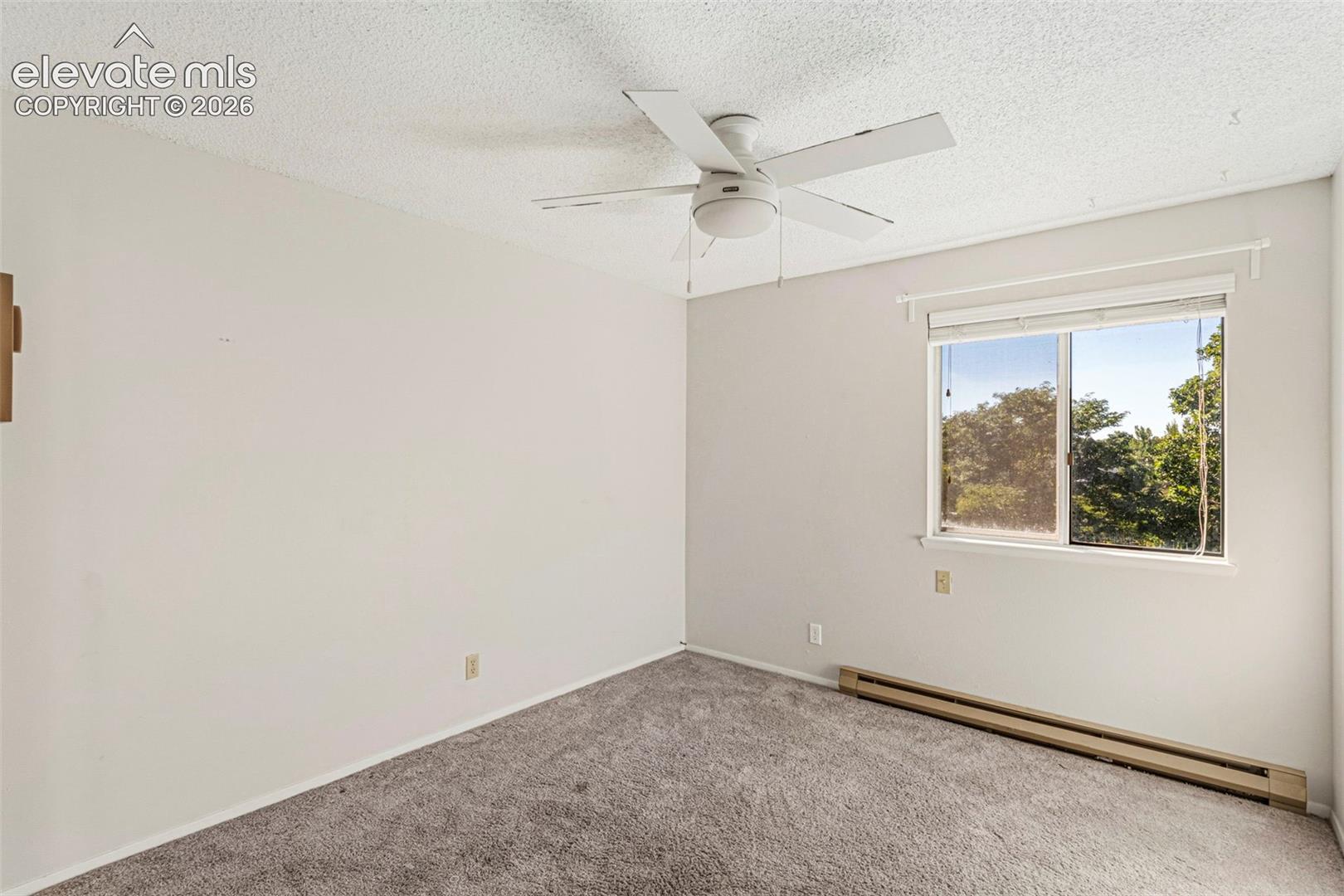 Room featuring neutral wall finishes, textured ceiling, gray carpeting, and a ceiling fan
