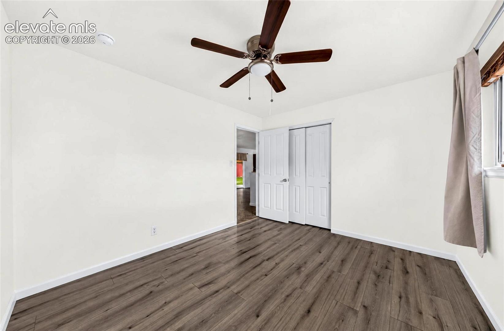 Wood-finish flooring, ceiling fan with integrated lighting, and multi-panel closet doors