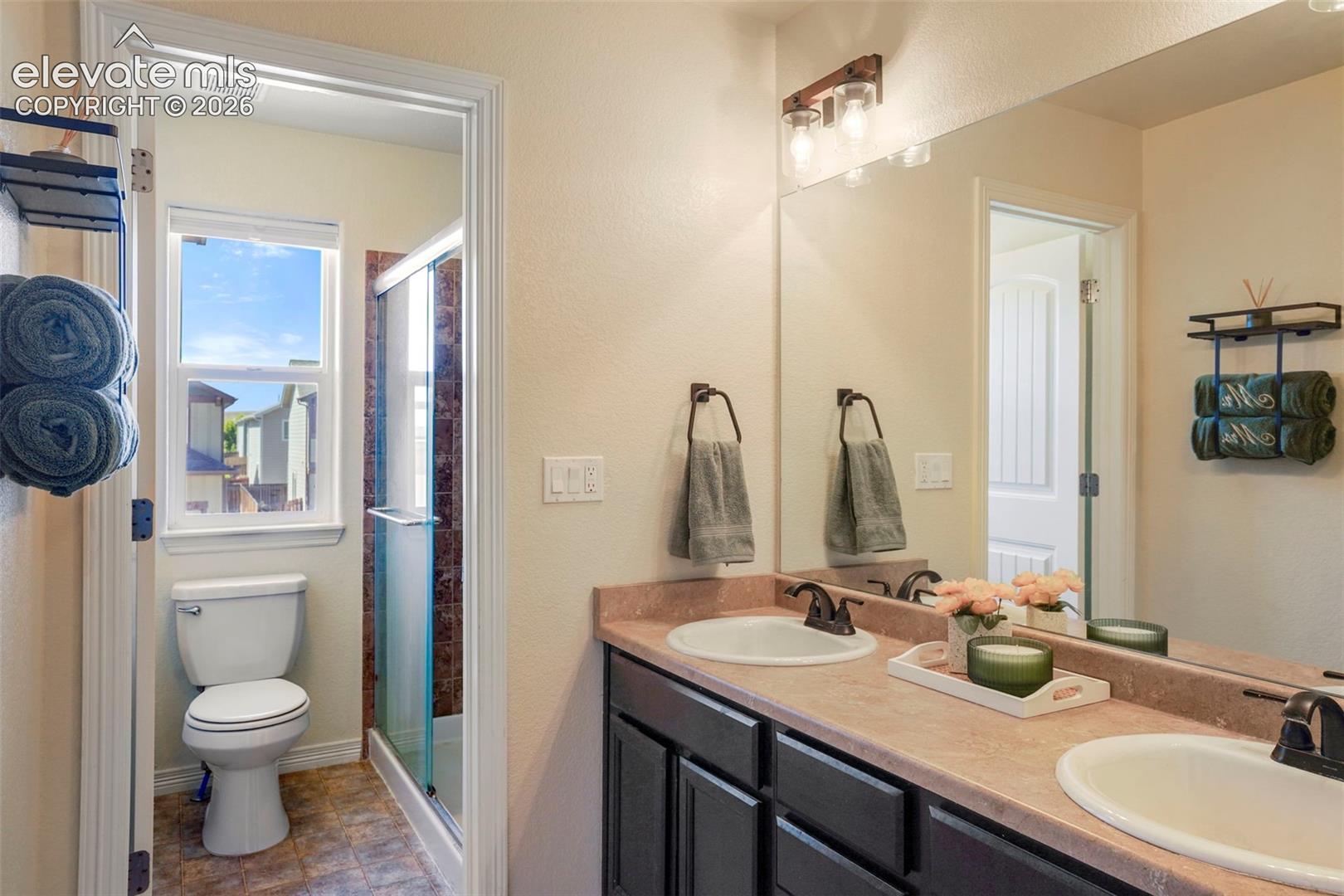 Dual vanity with undermount sinks, bronze finish faucets, and a large wall-mounted mirror