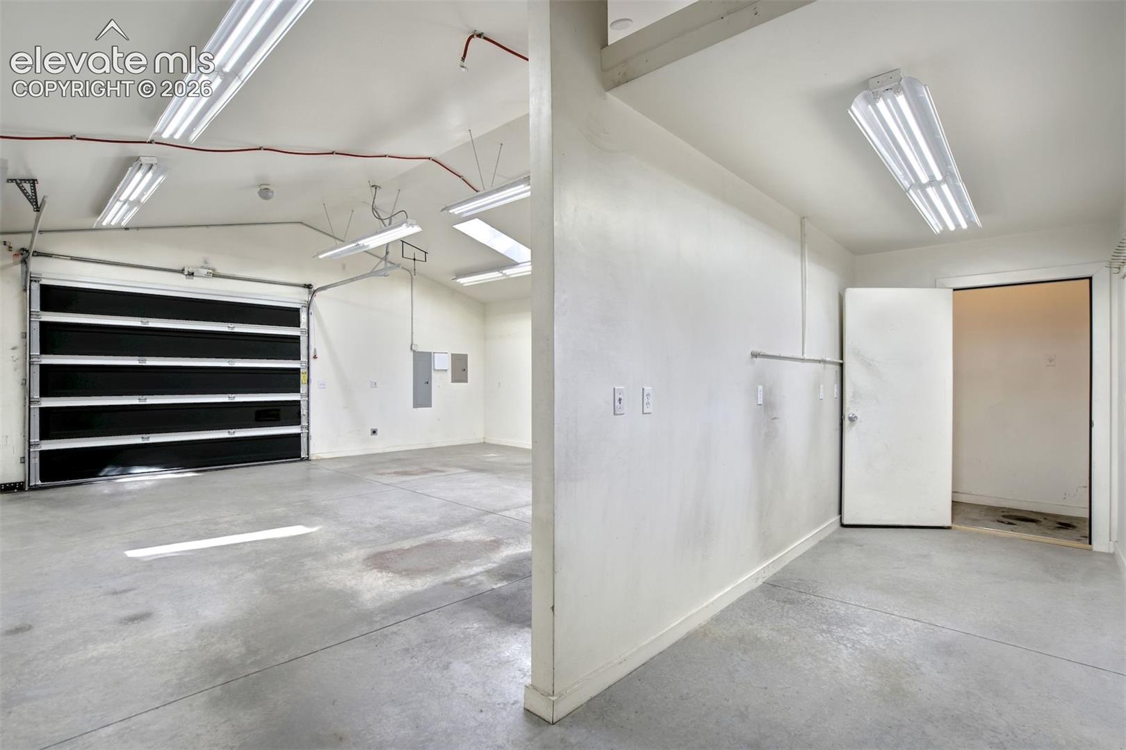 Multi-bay garage featuring concrete flooring, a sectional metal overhead door, and industrial-style ceiling-mounted lighting fixtures