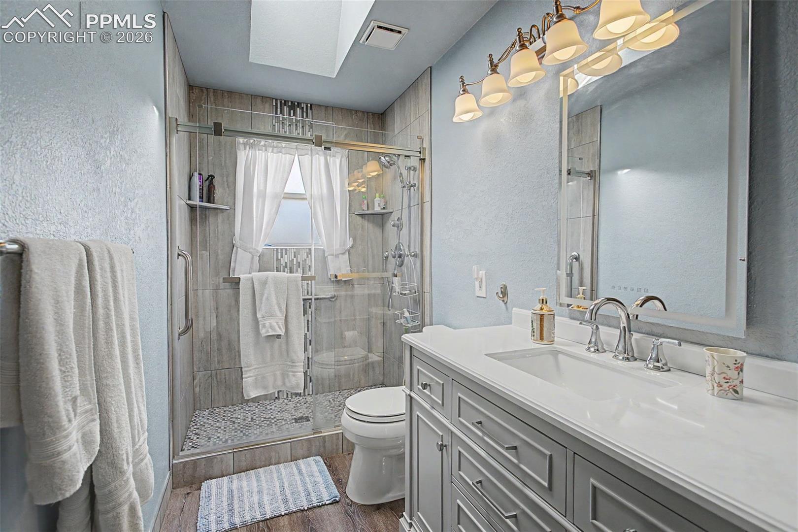 Upper level 3/4 bathroom, with skylight and floor-to-ceiling tiled walk-in shower.