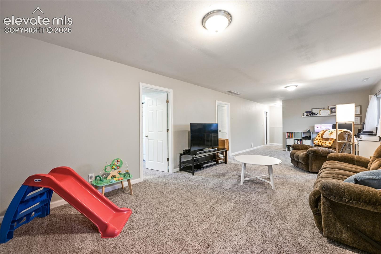 Neutral wall coloring, wall-to-wall carpeting, and multiple flush-mount ceiling light fixtures