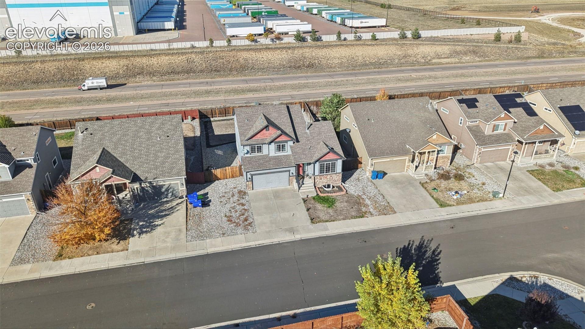 Aerial view featuring a two-story residence with a multi-gabled roofline, brick and horizontal siding exterior, concrete driveway, and attached two-car garage
