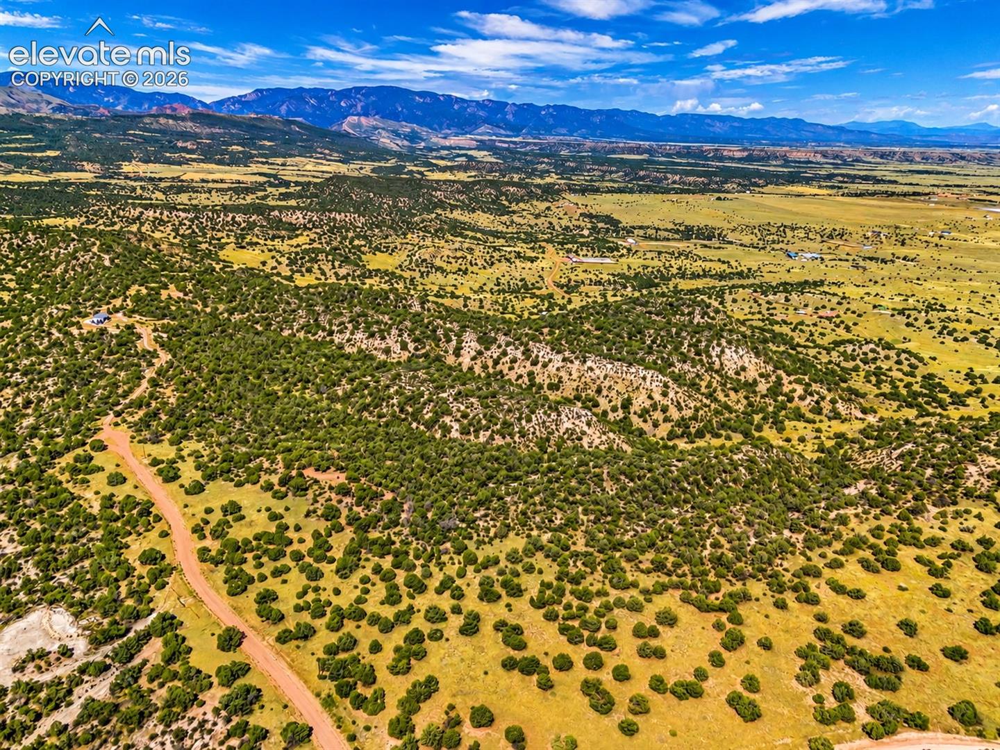 Breathtaking aerial perspective showcasing rugged ridgelines, open valleys, and spectacular mountain views. The property's varied terrain provides a picturesque setting surrounded by Colorado's natura

