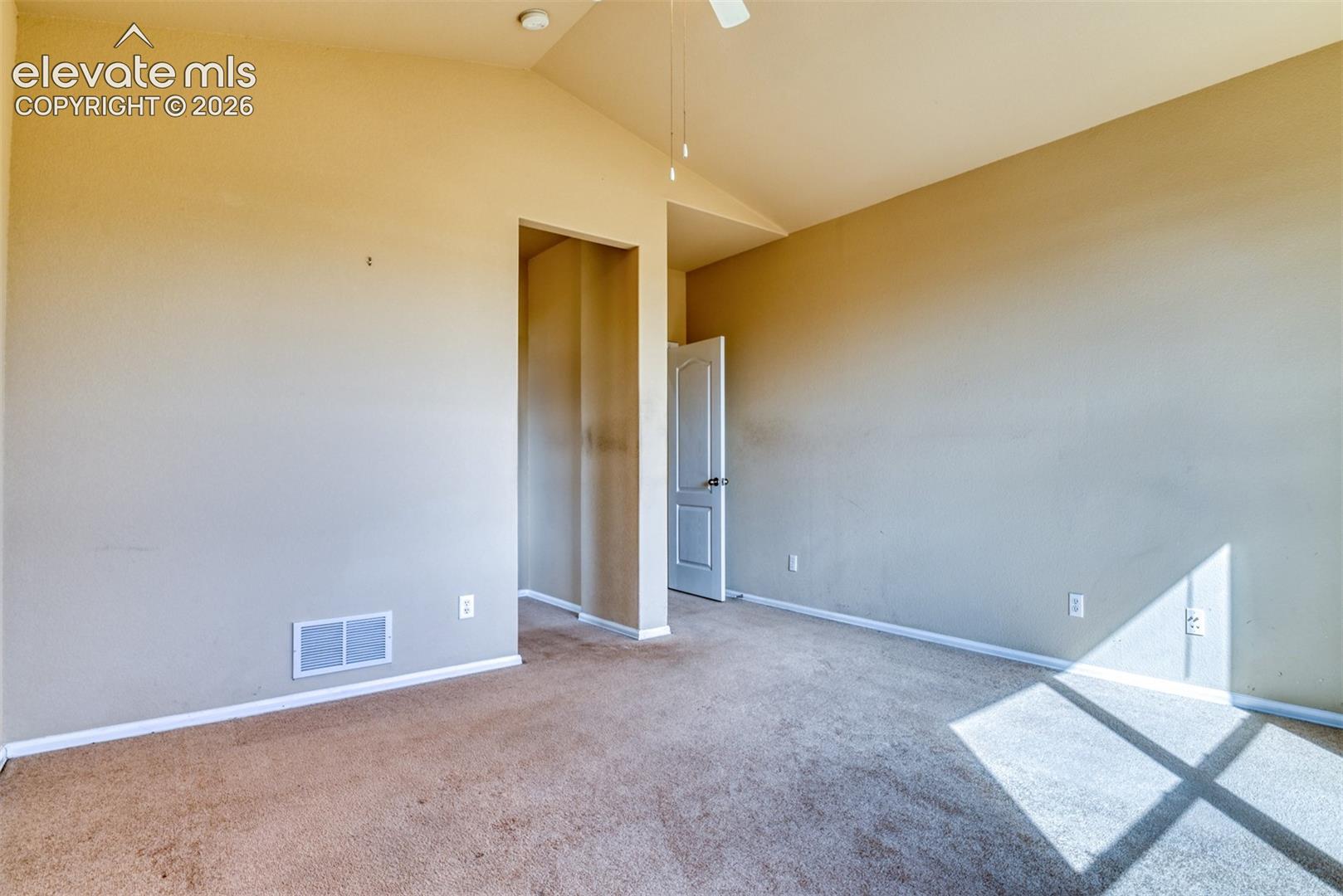 Vaulted ceiling featuring a ceiling fan and neutral wall-to-wall carpeting