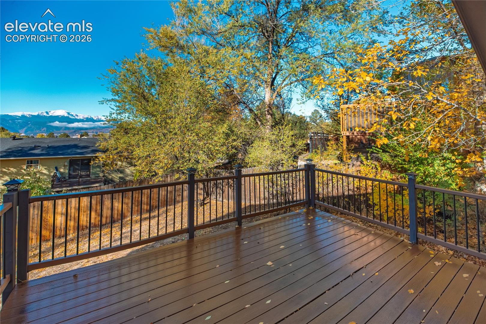 Elevated deck featuring wood-finish flooring, black metal railings, and mountain scenery
