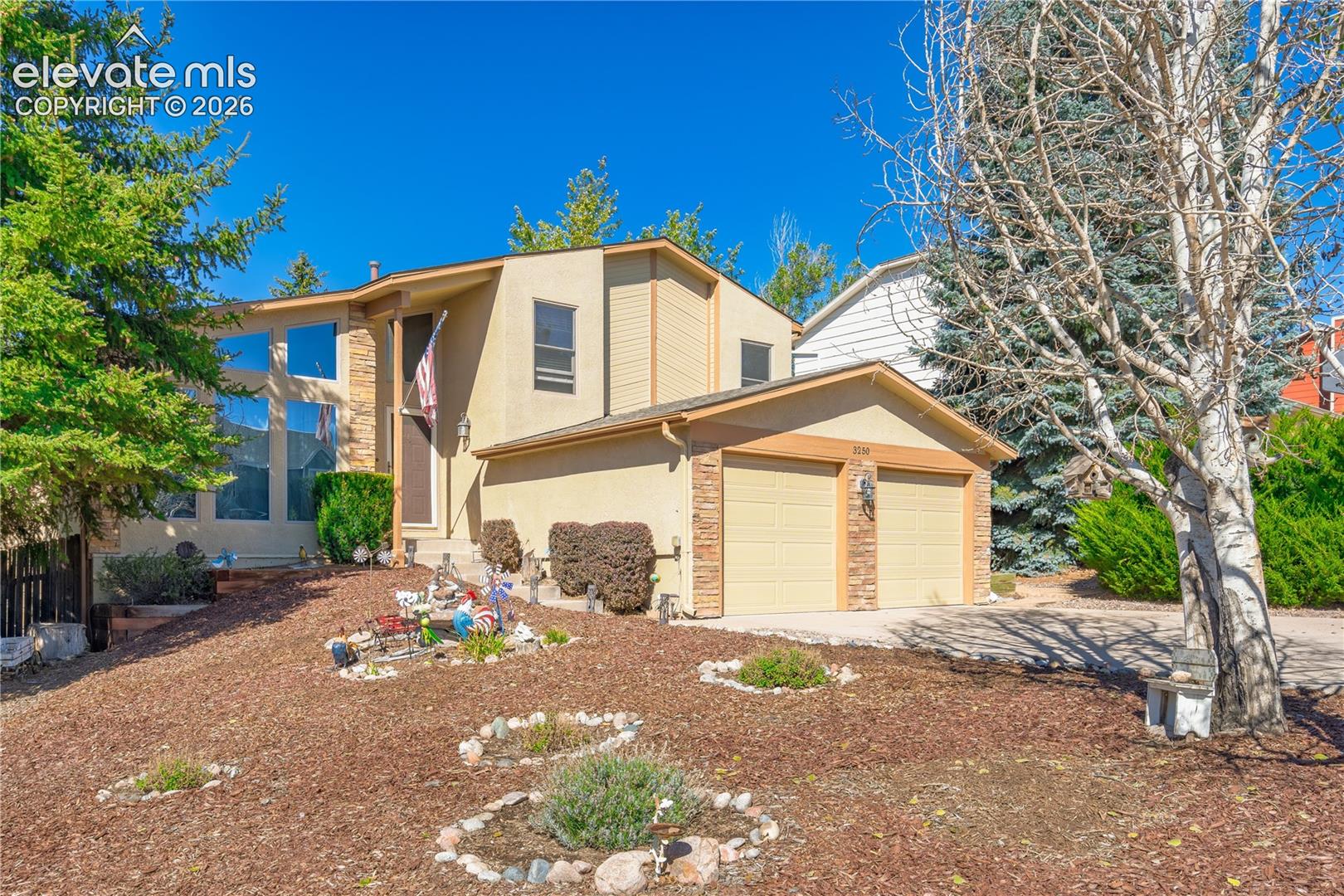 Split-level residence featuring a two-car garage with brick veneer accents and multiple large windows