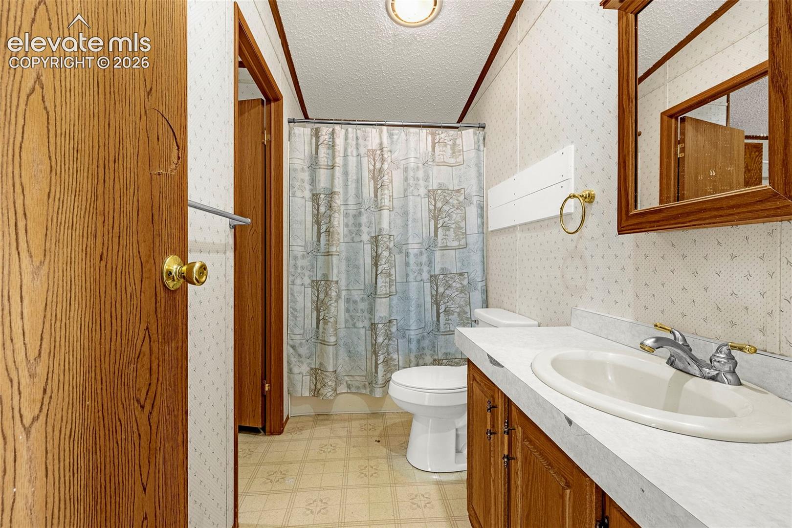 Bathroom featuring wood-finish cabinetry, a rectangular vanity countertop with an integrated basin, a wood-framed wall mirror, and a tub-shower combination