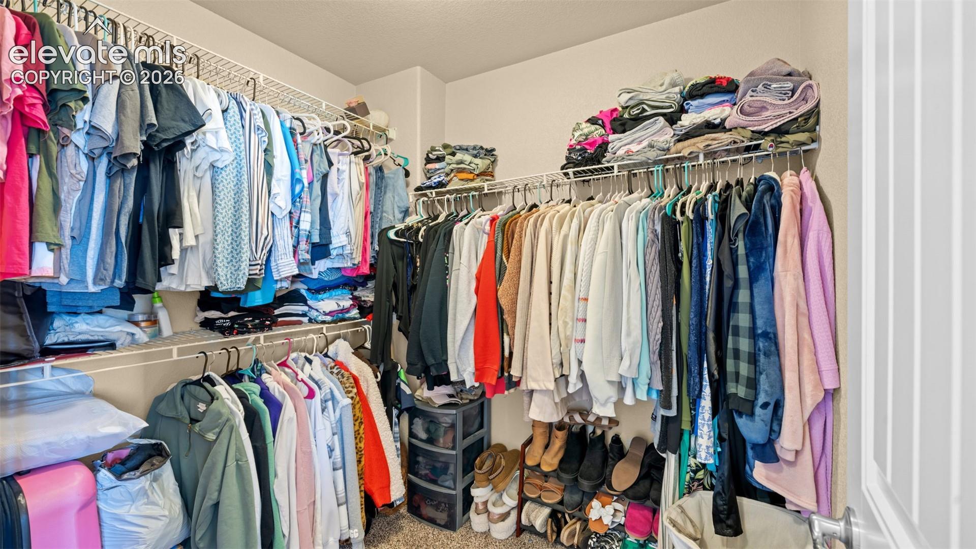 Primary Walk-in closet featuring wire shelving and multiple hanging rods