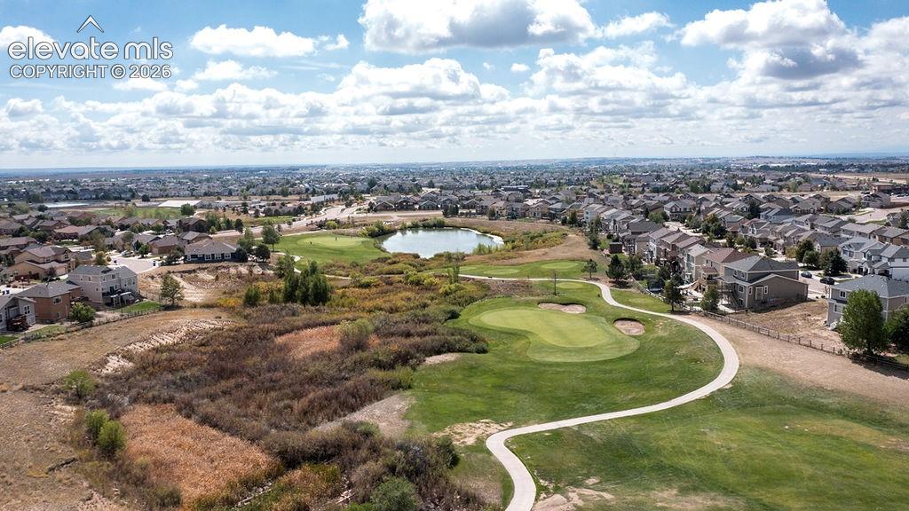 Expansive golf course setting featuring manicured greens, a golf cart path, and a serene pond