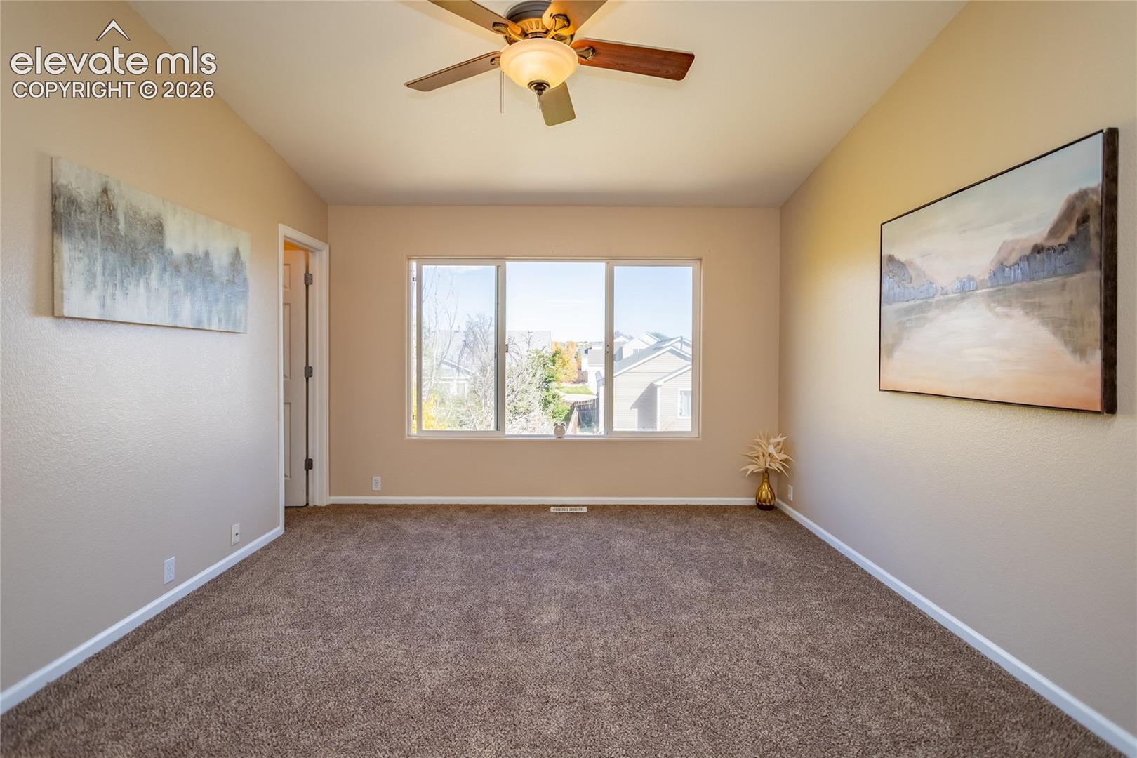 The spacious primary bedroom suite features brand-new carpet, vaulted ceiling, and a cooling ceiling fan