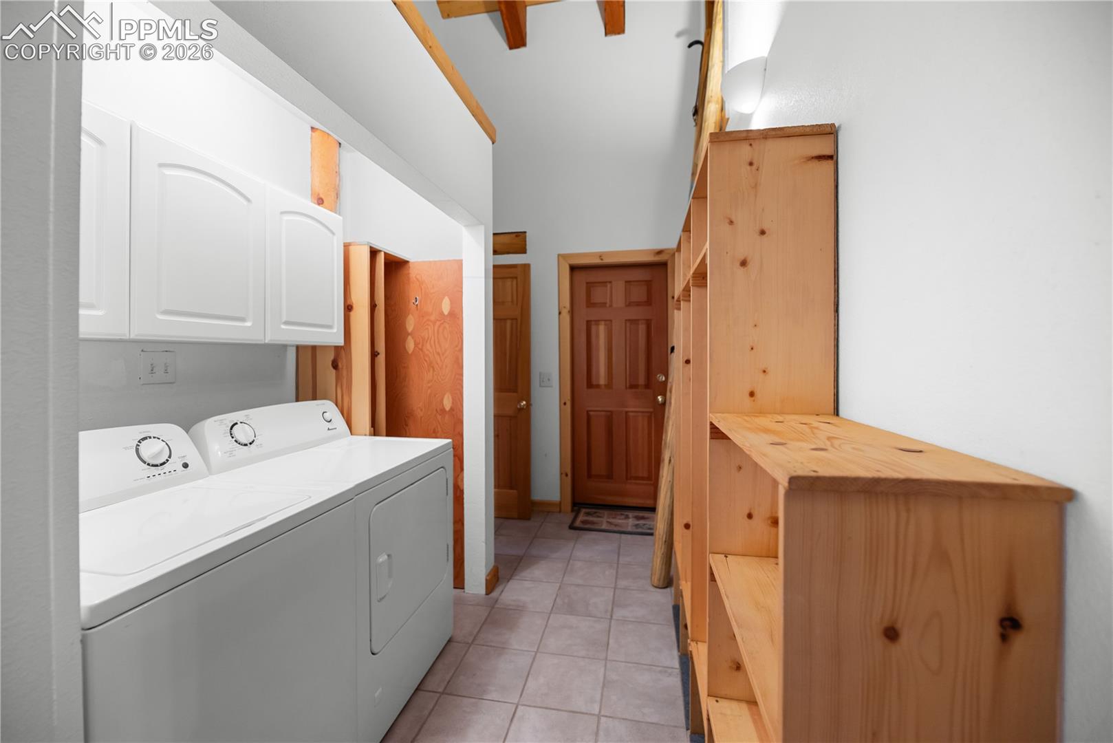 Laundry room featuring cabinet space, washer and clothes dryer, and light tile patterned floors