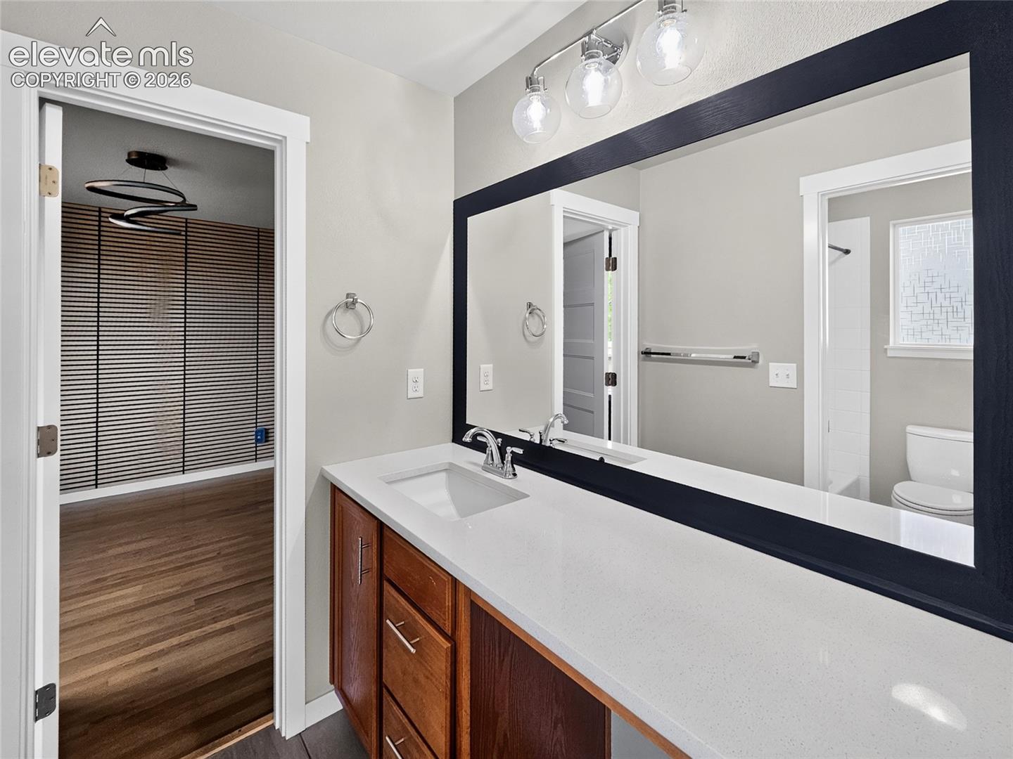 Bathroom vanity featuring a single basin sink, white countertop, and wood-finish cabinetry