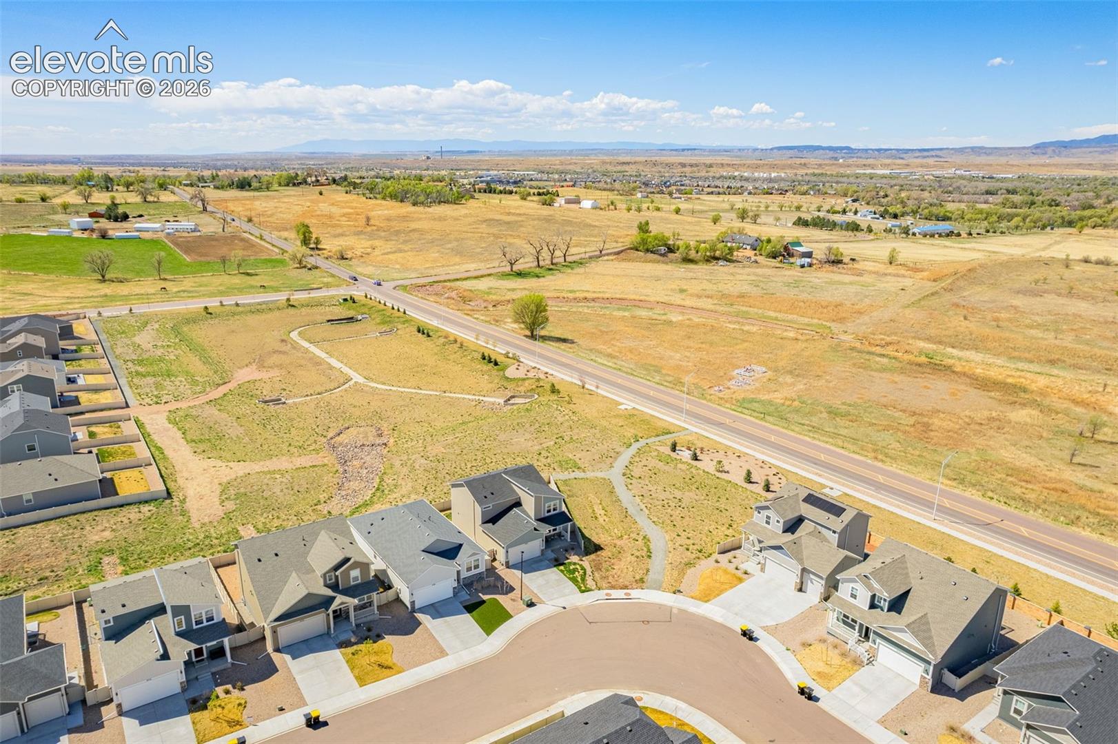 Residential neighborhood with cul-de-sac, adjacent to open fields and a paved road
