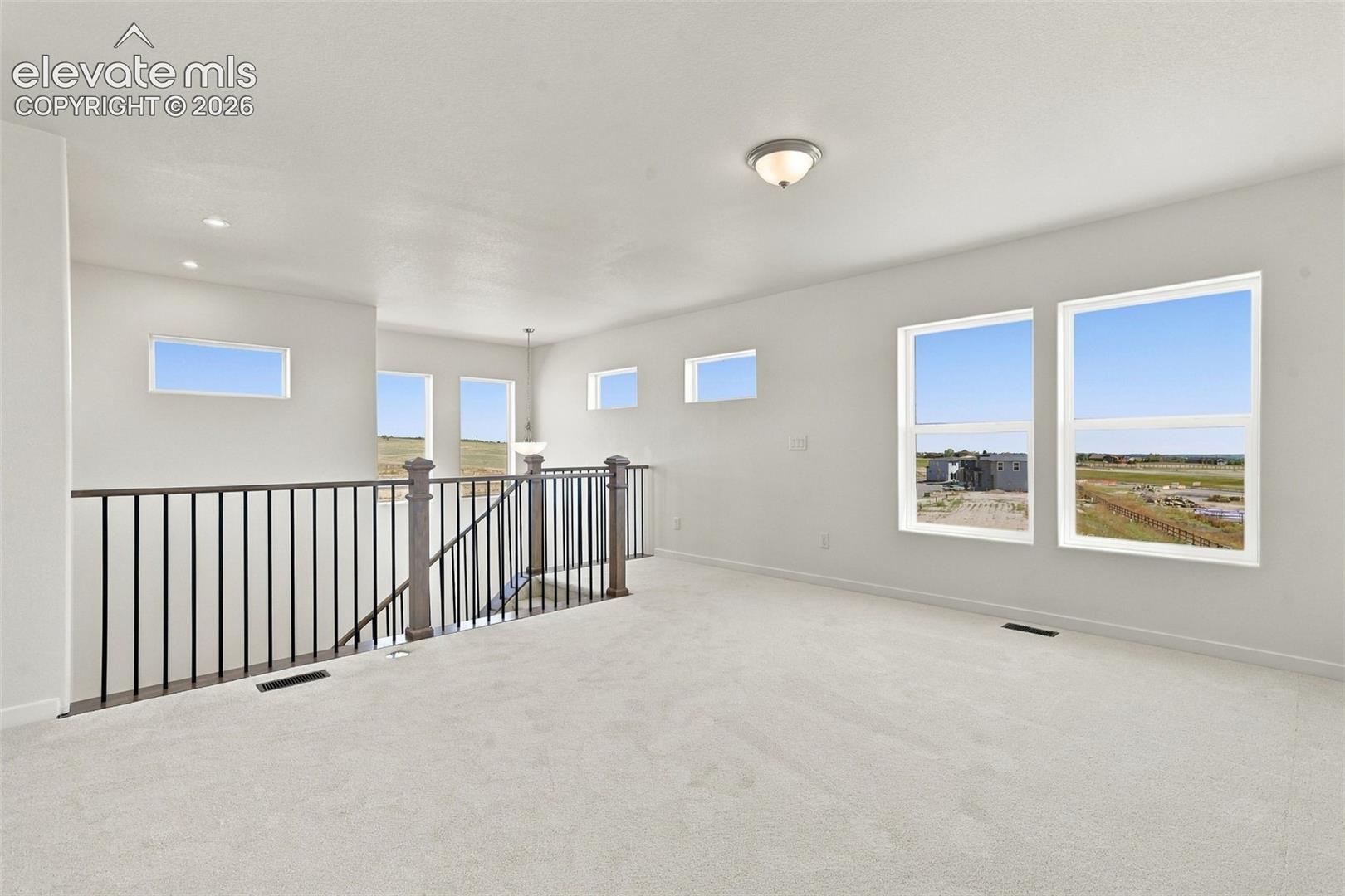 Spacious upper-level area with light-toned carpeting and multiple windows