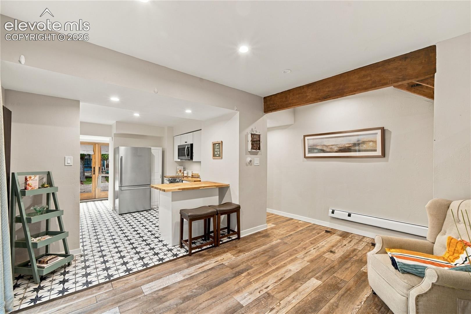 Kitchen featuring patterned tile flooring, wood-topped breakfast bar, recessed lighting, and an exposed wooden ceiling beam