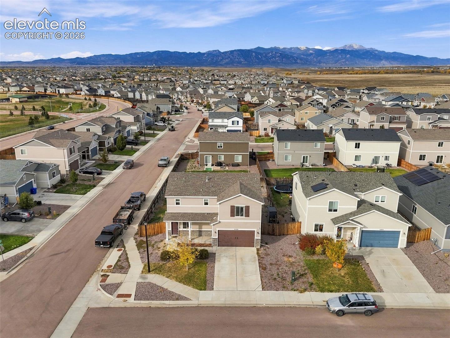 Two-story residential property featuring a composition shingle roof, attached garage, concrete driveway, and mountain backdrop