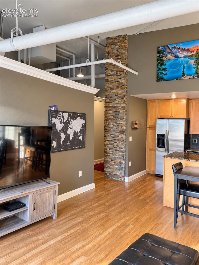 Hardwood flooring throughout, exposed ceiling ductwork, stone-clad pillar, crown molding, and recessed lighting