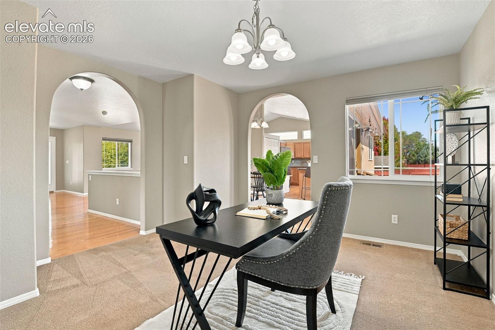 Spacious room featuring multiple arched doorways, a large window, and a chandelier-style light fixture