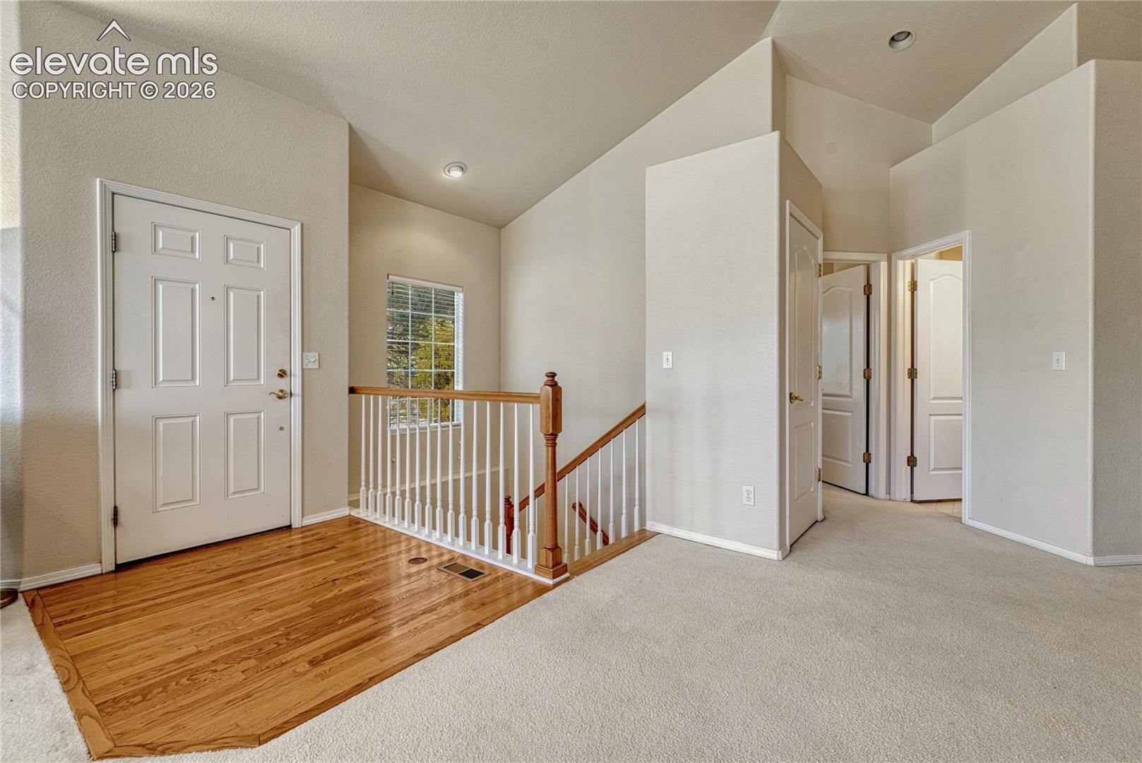 The front foyer features hardwood flooring and white painted spindles leading downstairs to the finished basement
