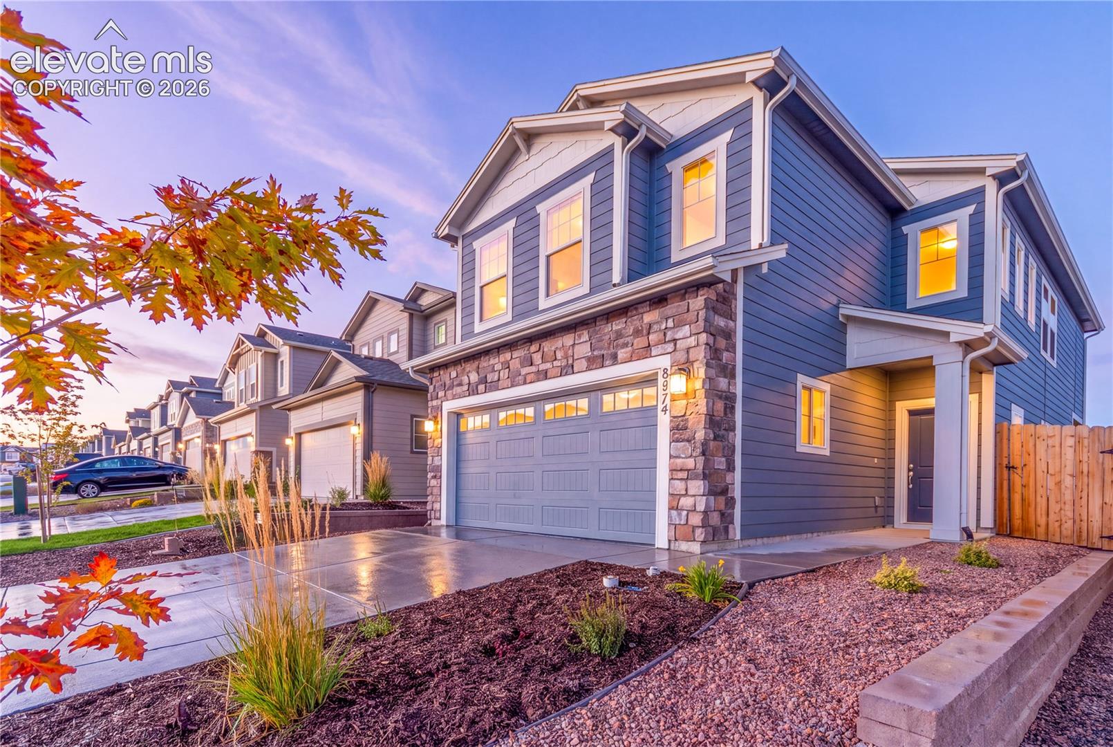 Two-story residence featuring horizontal lap siding, stone veneer accents, an attached garage, and a concrete driveway