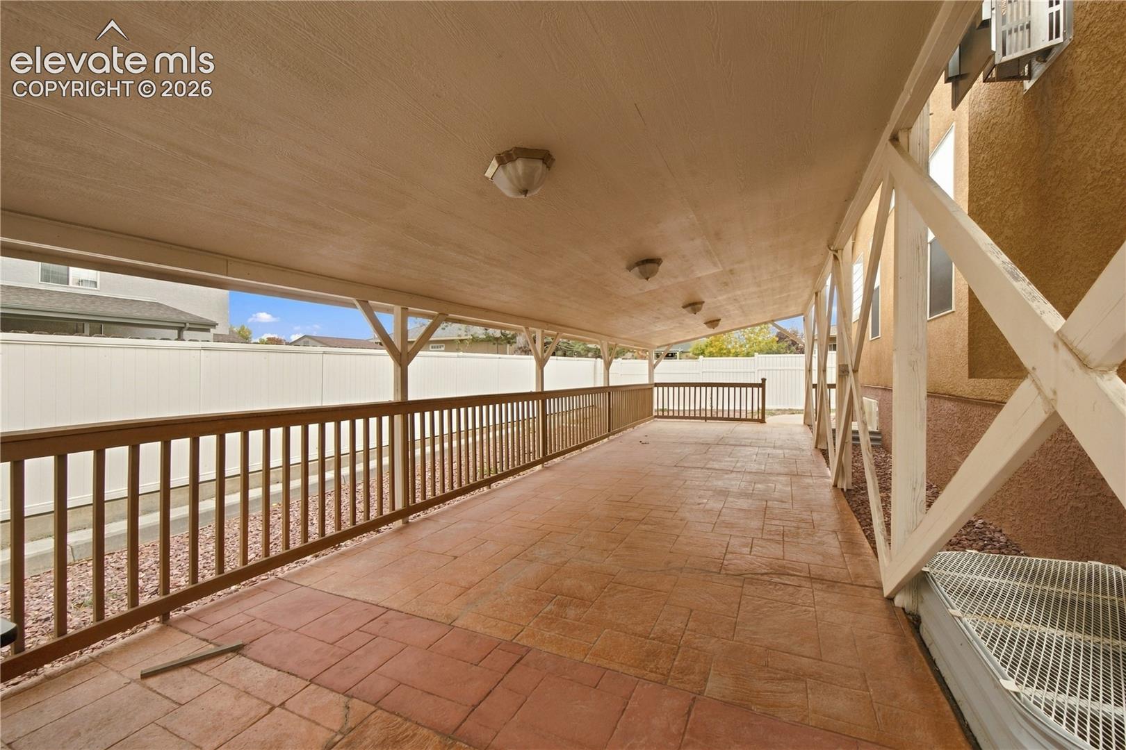 Covered patio featuring stamped concrete flooring, wood-finish railing, and recessed ceiling lighting