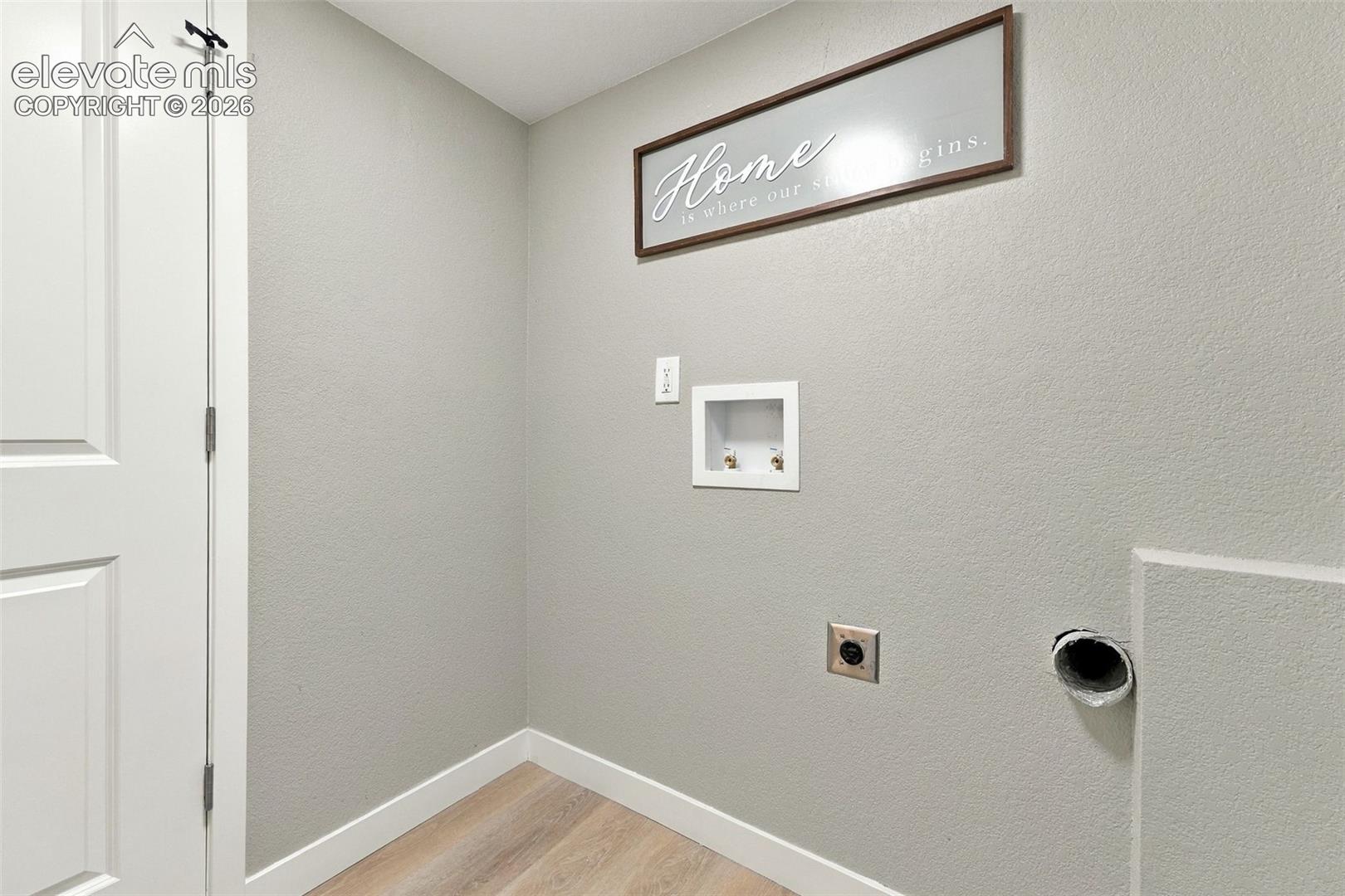 Utility space featuring wood-finish flooring, a recessed water supply box, and dedicated dryer venting