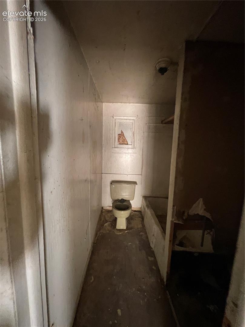 Bathroom featuring a standard toilet, built-in bathtub, and a wall-mounted window