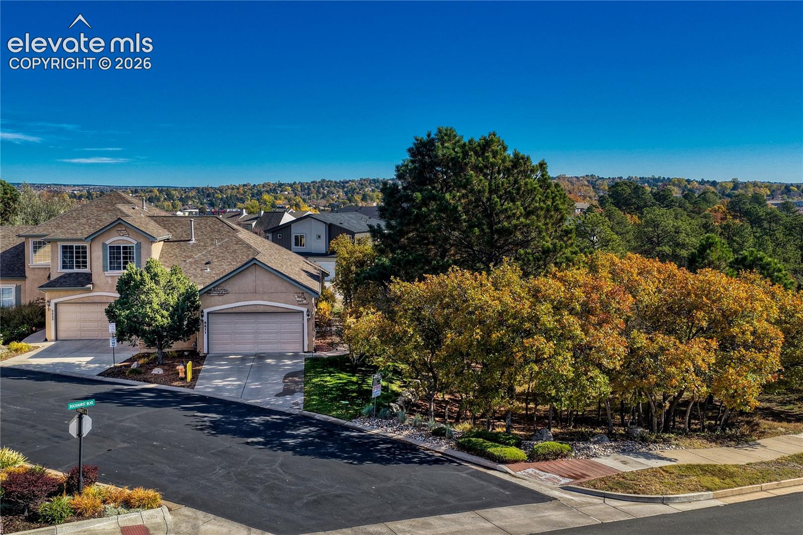 Elevated aerial shots highlight the premium end-unit location bordered by mature trees and open space
