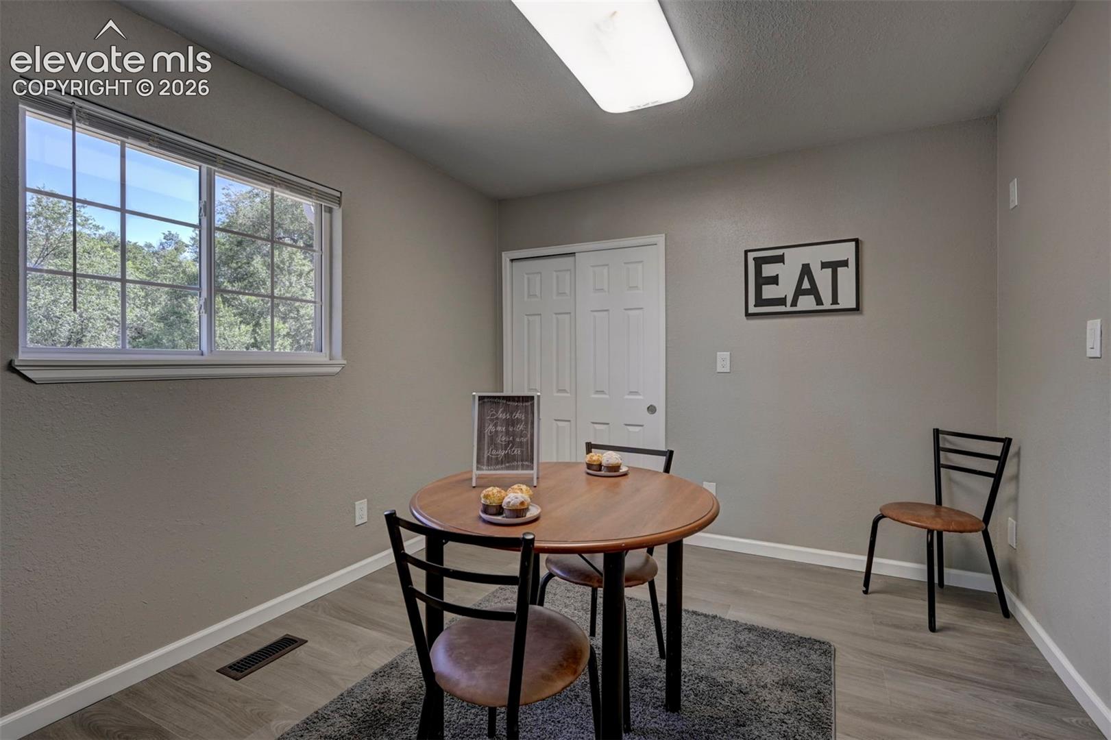 Room featuring wood-finish flooring, a dual-pane sliding window, and a white six-panel closet door