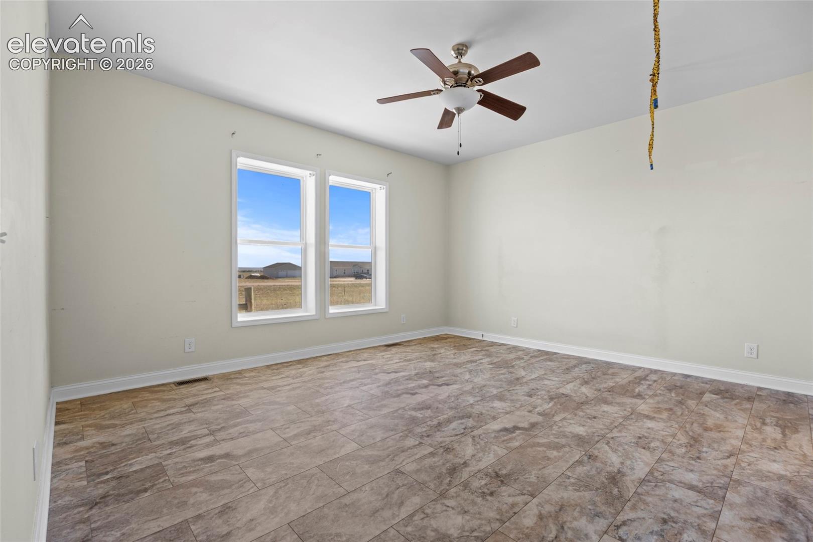 Room featuring tile flooring, dual windows, and a ceiling fan with light fixture